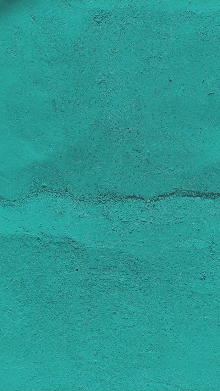 A close-up of a turquoise concrete wall showcasing rough texture and minimalist design.
